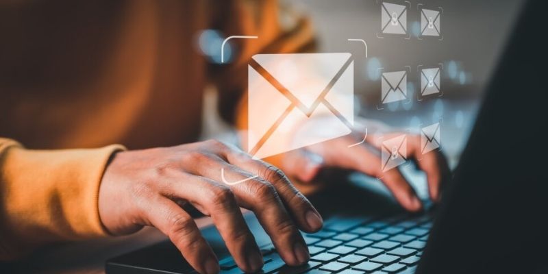 Pessoa digitando em laptop com ícones de e-mail ao fundo