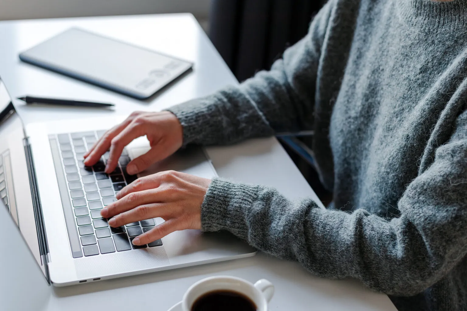 Pessoa digitando em laptop com café ao lado