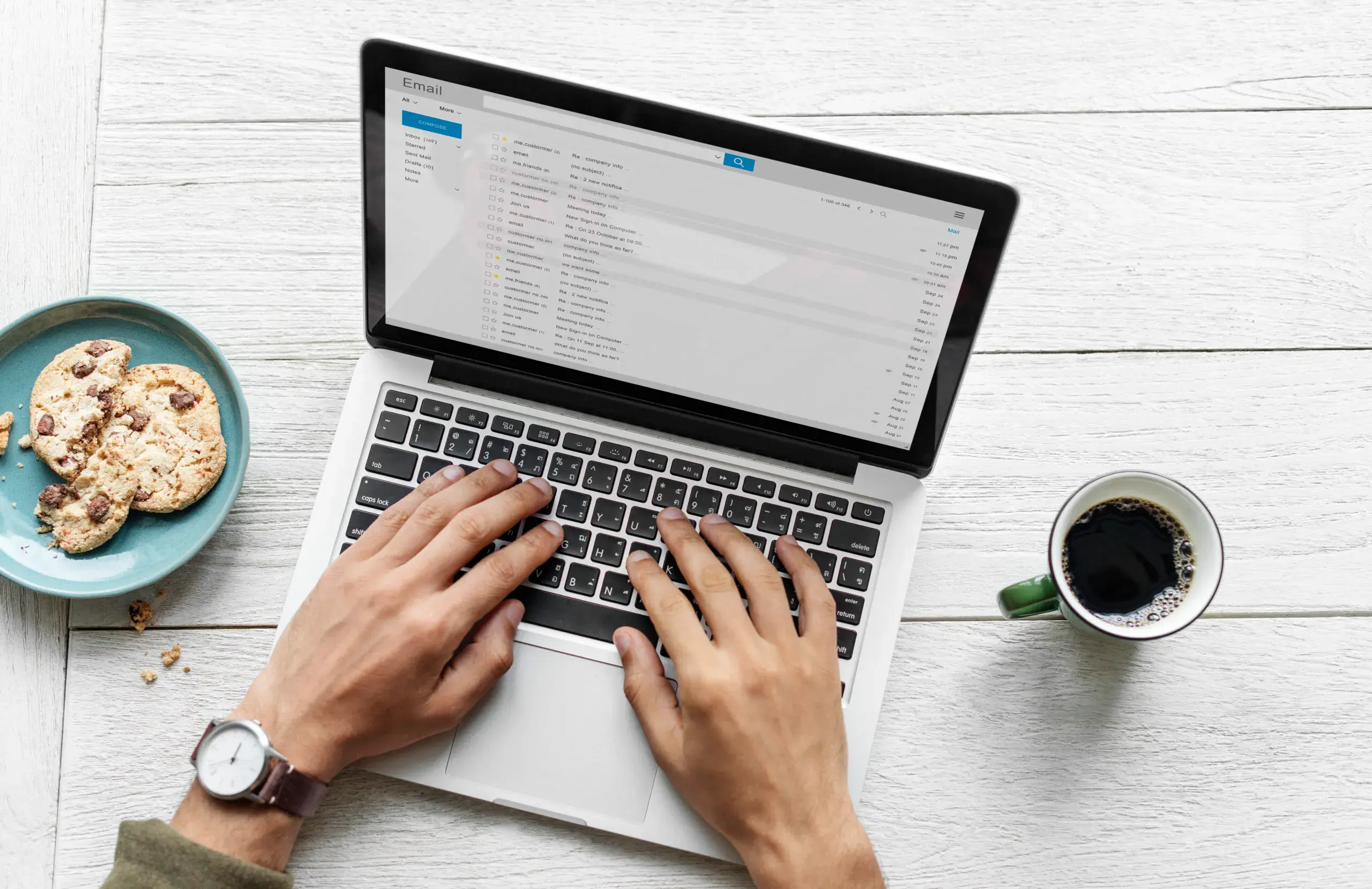 Pessoa digitando em um laptop com café e biscoitos
