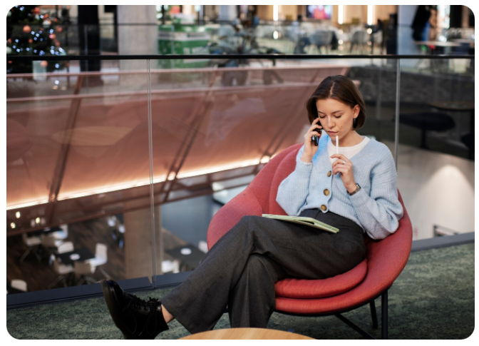 Uma mulher sentada em uma cadeira falando no telefone.